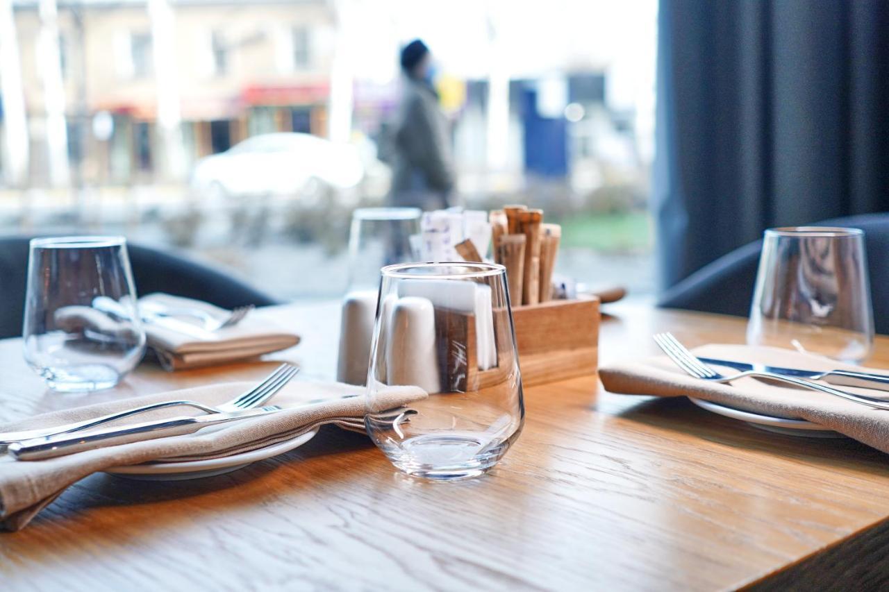 Novotel Bishkek City Center Extérieur photo A restaurant table set with a glass, a plate, a napkin, and a knife and fork